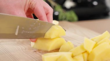 Makro. Çiğ patatesler keskin bir bıçakla, tahta bir tahtayla parçalara ayrılır. Patates tabağı, patates püresi, haşlanmış patates turta ve abur cubur. Yakın plan, kenar görünüm