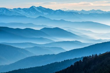 Ufuk çizgisine uzanan sisli dağ sıralarının nefes kesici görüntüsü mavinin tonlarıyla katmanlı bir etki yaratıyor. Yumuşak sis rüya gibi bir atmosfer ekler. Bu da onu dingin doğanın, sükunetin ve uçsuz bucaksız manzaraların mükemmel bir temsilcisi yapar.. 
