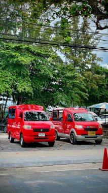 Tayland, Phuket 13 Aralık 2024 - İki Tayland geleneksel kırmızı tuk-tuk taksi (songthaew). Kırmızı tuk-tuk taksisi yol boyunca park halinde..