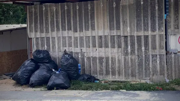 Siyah poşetlerdeki çöpler yolun kenarındaki çitin altında düzgünce istiflenmiş..