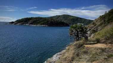 Kayalık kıyısı ve mavi suyu olan deniz burnu. Arka planda adanın yeşil tepeleri. Gözlem güvertesinden görüntü. Konsept: Seyahat, doğa, tatil, tropikal cennet, eko-turizm, deniz özgürlüğü, bilgisayar duvar kağıdı.