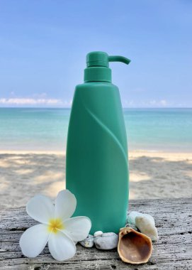 Plaj arka planında şeker kutusu olan turkuaz bir şişe. Kozmetik, vücut bakımı ve SPA ambalaj modeli. Tropiks, doğallık, aroma, yaz, organik, güzellik, rahatla.