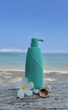 Plaj arka planında şeker kutusu olan turkuaz bir şişe. Kozmetik, vücut bakımı ve SPA ambalaj modeli. Tropiks, doğallık, aroma, yaz, organik, güzellik, rahatla.