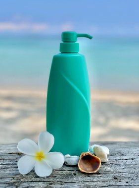 Tropik plaj arka planında pompa dağıtıcısı olan turkuaz plastik şişe. Frangipani çiçeği, deniz kabuğu ve çakıl taşları doğal bir spa ve cilt bakımı sağlar. Yaz, güzellik, sağlık, doğal kozmetik ve plaj yaşam tarzı kavramları için mükemmel..
