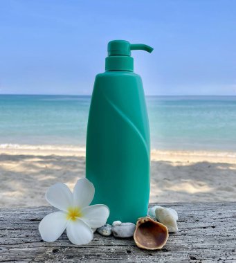 Tropik plaj arka planında pompa dağıtıcısı olan turkuaz plastik şişe. Frangipani çiçeği, deniz kabuğu ve çakıl taşları doğal bir spa ve cilt bakımı sağlar. Yaz, güzellik, sağlık, doğal kozmetik ve plaj yaşam tarzı kavramları için mükemmel..