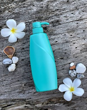 Frengipani çiçeklerinin, kabukların ve eski odunların arasında şeker kutusuyla turkuaz şişe. Doğal kozmetik ürünleri, vücut bakımı, SPA, yaz, doğa ve eko-stil.