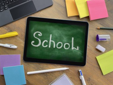 Okul panosunu taklit eden yeşil bir tablet ve tahta bir masanın üzerinde 
