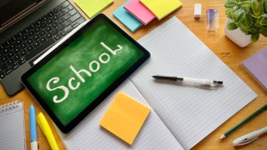 Masanın üzerinde yeşil bir geçmişi olan bir tablet var. Üzerinde 