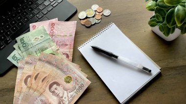 Not defteri ve hesap makineli Tayland paralarının üst görüntüsü. Güneydoğu Asya 'da muhasebe, seyahat, ekonomi ve kişisel finans kavramı.