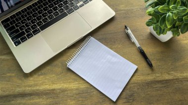 Dizüstü bilgisayar, not defteri ve kalem ahşap masa, görev planlaması konsepti ve ofiste veya evde verimli çalışma.