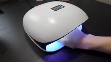 Manikür sırasında jel cilasını iyileştirmek için ultraviyole lambanın altındaki elin kısa videosu..