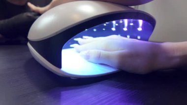 Jel manikürü için UV / LED lambanın altında bir elin iyileştiğini gösteren kısa bir video. Yakın çekim - bir lambalı kadın elleri video.