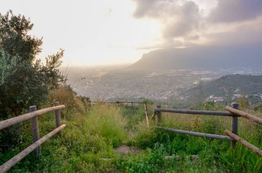 Tahta çitlerle çevrili, aşağıdaki vadideki uzak bir dağ ve şehir manzarasına açılan bir görüntü. Seyahat, doğa ya da manzara teması için ideal. Manzaralı bir yolculuk yakalar