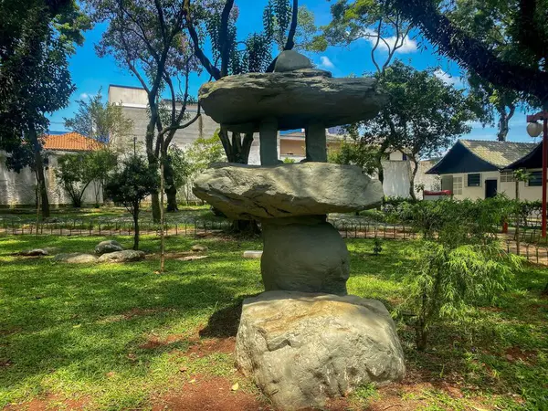 Yeşil ağaçlar ve açık mavi gökyüzü ile çevrili güzel bir parkta istiflenmiş heykel. Doğal sanat eserleri huzur ve uyum hissi getirir, rahatlama ve tefekkür için idealdir..