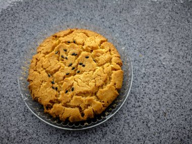 Seramik yüzeyde plastik mika ile siyah susamlı kuru kurabiyeler.