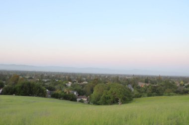 Arka planda mavi gökyüzü olan çayır ve dağların manzarası