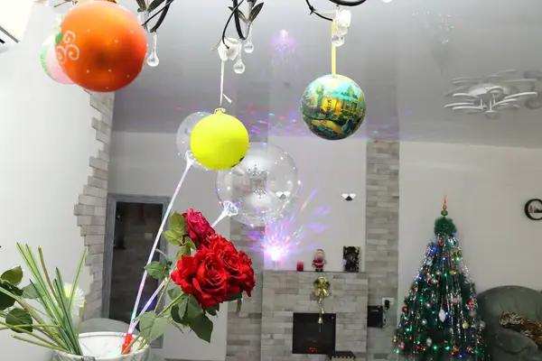 Noel ağacının arka planında kırmızı güller ve balonlar.