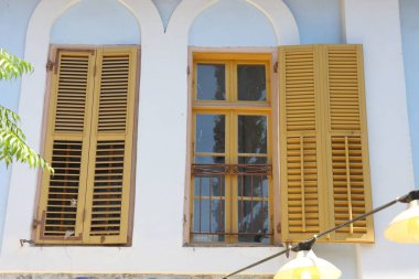 Binanın duvarında panjurları olan eski ahşap bir pencere..