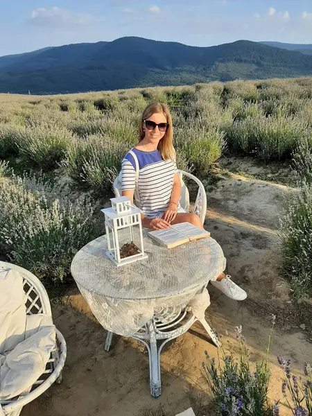 Genç bir kadın arka planda lavanta ile oturup rahatlıyor.