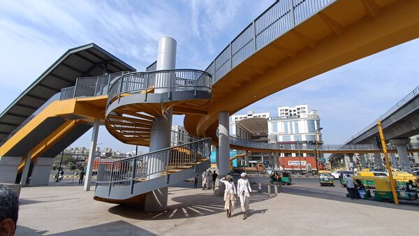 a street view with the walk way taking to the metro station and people commuting. Blue sky sky walk. Location Ahmedabad, Gujarat, India on 12 Mar 2023 