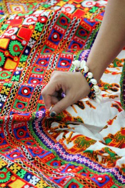 hand of a woman holding the fabric of her beautifully woven traditional skirt. Kachhi kanch embroidery with beautiful colors of thread. attire for Garba in Navratri festival  clipart