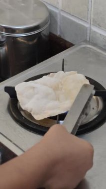 Ev mutfağındaki geleneksel pişirme işlemi sırasında maşa kullanarak gazlı fırında pişen Hint Roti 'si..