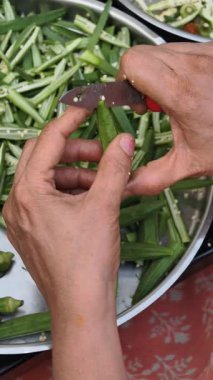 Geleneksel Hint ev yemeği hazırlamak ve pişirmek için taze bamya dilimleyen yaşlı ellere yakın plan..