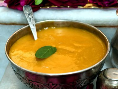 Lezzetli ev yapımı mango hamuru. Geleneksel gümüş kâse, kaşık ve kutsal fesleğen yaprağı garnitüründe servis edilir. Hint mutfağını, dini geleneği ve şenlikli lezzetleri sembolize eder.
