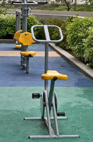 Renkli, yeşil bir spor salonunda bisiklet makinesi ve omuz presi olan boş spor aletleri sağlıklı yaşam tarzını ve toplum sağlığını destekliyor..