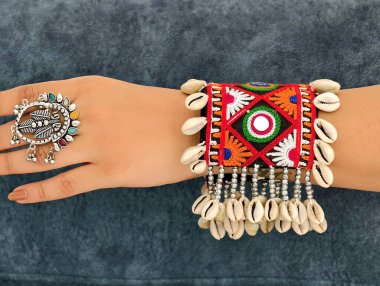 El, canlı işlemeli Navratri kada bileziği takıyor Kodi kabukları ve oksitlenmiş yüzükle süslenmiş, mükemmel bir Hint-batı geleneği ve şenlik zarafeti sergiliyor..