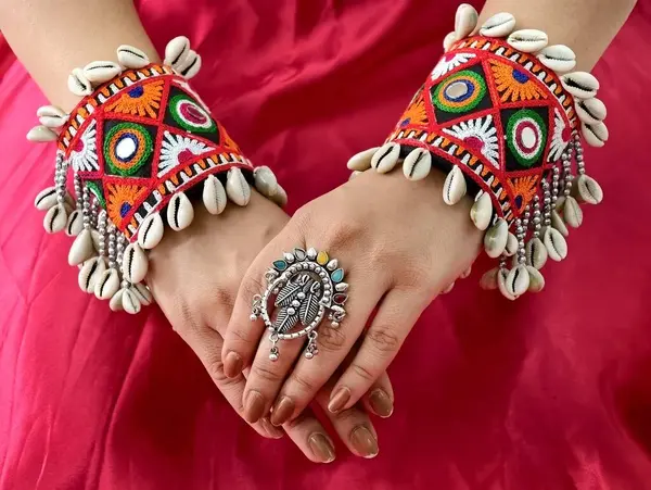 Renkli Navratri Kodi kabuğu işlemeli el feneri bilezikleri oksitlenmiş yüzükle şekillendirilmiş, geleneksel Hint sanatını cesur Hint-batı şenlik modayla harmanlıyor..