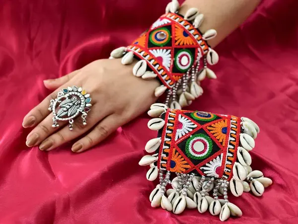 El, canlı işlemeli Navratri kada bileziği takıyor Kodi kabukları ve oksitlenmiş yüzükle süslenmiş, mükemmel bir Hint-batı geleneği ve şenlik zarafeti sergiliyor..