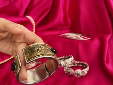 Geleneksel oksitlenmiş bilezikler ve süslü kol bileziği canlı pembe saten bir arka planda gösteriliyor. Etnik stil ve Navratri festivali için mükemmel.