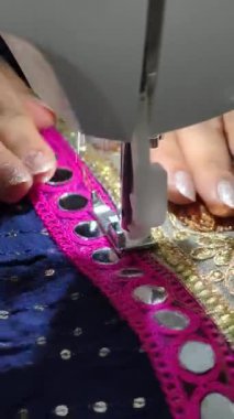 Navratri 'nin garba çalması için Chaniya Choli' yi dikmek için dikiş makinesi kullanılarak dikilen aynalı işlemeli dantelin yakın çekimi. Tekstil sanatında gelenek ve işçiliğin birleşimi.