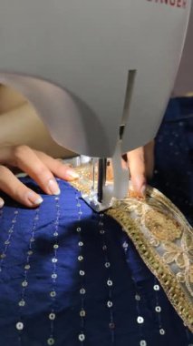 Dikiş makinesini odaklı ışıklandırma altında kullanarak geleneksel işlemeli dantel ören ellerin yakın çekimi. Chaniya Choli Navratri 'de garba çalacak. Dikiş işlemi devam ediyor. 