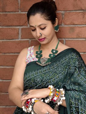 Oksitlenmiş kumaş mücevherleri ve renkli kodi bilezikleriyle geleneksel yeşil bantlı sari giyen kadın, shravan ayında Hindu şenlik havasında Hariyali Teej 'i arıyor. Hint etnik giyimi. 