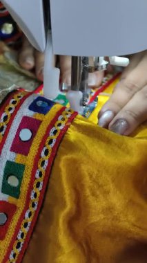 Geleneksel bağcıkları aynayla canlı ipek bir Chaniya choli 'ye dikmek, Navratri için her iplikle el yapımı detaylar ve şenlik hazırlığının güzelliğini yakalamak..