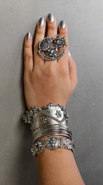 Geleneksel oksitlenmiş gümüş takılarla süslenmiş zarif bir el. Karmaşık Hint işçiliği sergileniyor. Cesur yüzükler, Navratri festivali için antika bilezikler ve Hint-batı görünüşü. 