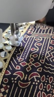Ayna işleme işi dikiş makinesindeki jrak desenli kumaşa dikilmek, geleneksel Hint tekstil işçiliği ve hassas terziliği sergiliyor. Chaniya Choli Navratri için hazırlanıyor. 