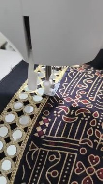 Ayna işleme işi dikiş makinesindeki jrak desenli kumaşa dikilmek, geleneksel Hint tekstil işçiliği ve hassas terziliği sergiliyor. Chaniya Choli Navratri için hazırlanıyor. 