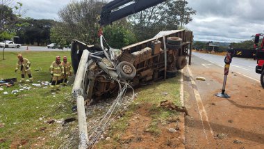 Yol kenarında bir kamyon devrildi. Etrafı itfaiyecilerle çevriliydi. Olay yeri kazanın şiddetini, enkazın dağılmasını ve kurtarılmanın aciliyetini yakalıyor. Bulutlu gökyüzü ve arka plan bitki örtüsü kontrastı.