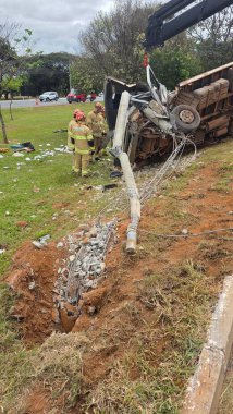 Bir direğe çarpan bir kamyonun karıştığı bir kaza mahalli. İtfaiyeciler, enkaz ve devrilmiş tellerle çevrili yeşil bir çimenlikte özenle çalışıyorlar. Bulutlu gökyüzü, acil servis olarak gergin ve acil bir atmosferi yansıtıyor