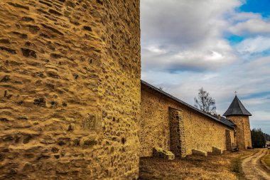 Taş duvarlı eski ortaçağ kalesi, bulutlu mavi gökyüzü.