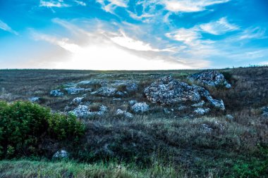 landscape with a rocky mountain and a cloudy blue sky.