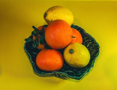 Kırmızı tabakta portakal, mandalina ve yeşil elma.