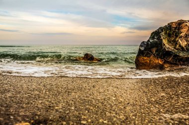 Gün batımında deniz manzarası ve kıyıda dalgalar