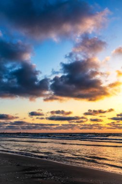 Güzel bulutları ve dramatik gökyüzü olan bir plajda gün batımı