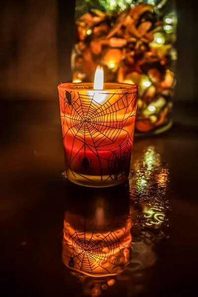 Karanlık bir arka planda, bir bardakta mum