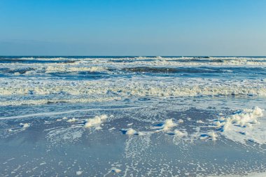 Beyaz köpüklü ve mavi gökyüzüyle güzel bir sahil..