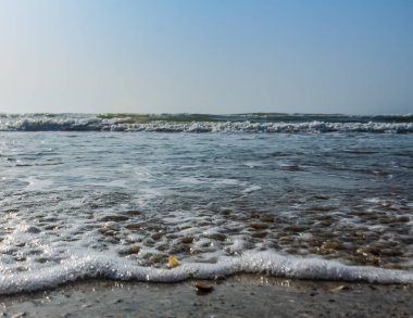 Kumlu bir sahilde deniz dalgaları.